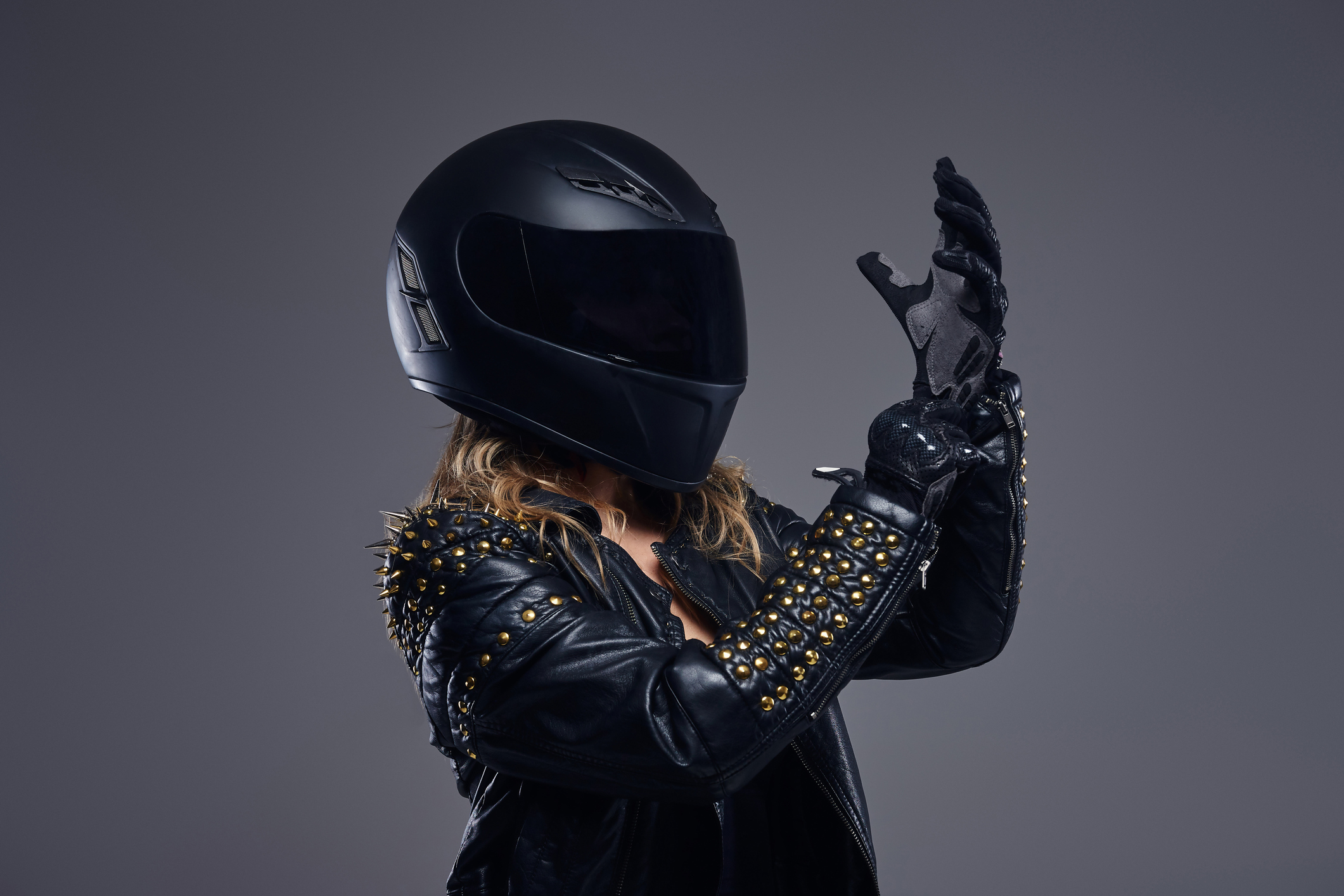 biker girl wearing leather race costume and protective helmet putting on gloves